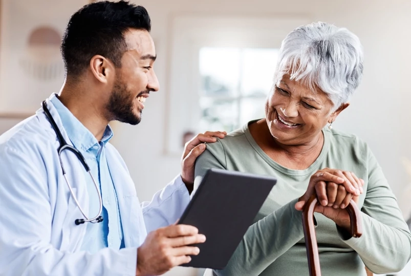 A doctor with his hand on a female patient's shoulder as he discusses her health plan during a checkup.