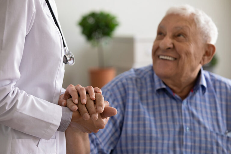 A patient holds the hand of a doctor during a routine checkup.