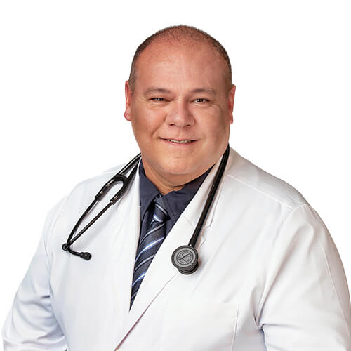 A headshot of Dr. Carlos Olivera, M.D., wearing a grey shirt and tie under a white lab coat with a stethoscope around his neck.