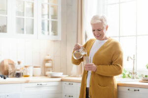 senior pour water into glass for hydration
